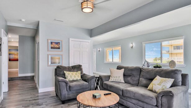 A spacious living room with grey sofas, a wooden coffee table, and a ceiling fan. - Atlantic Sunrise Home (Daytona Beach Shores)