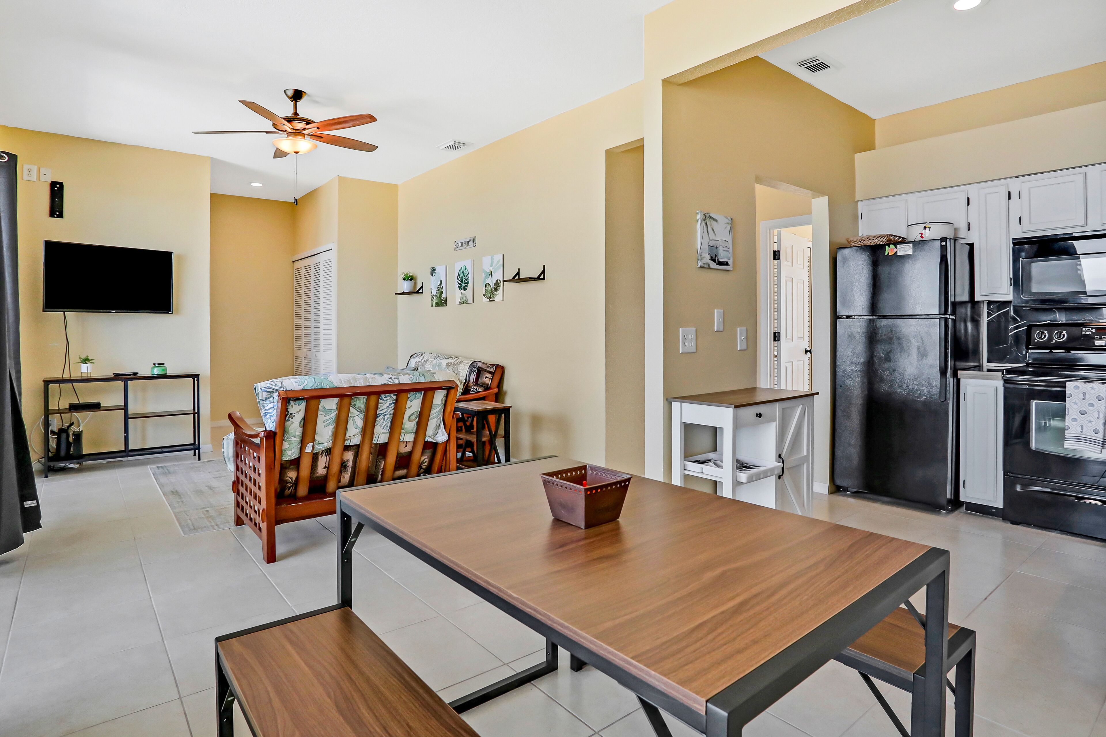 A modern kitchen with a built-in oven, microwave, and refrigerator. There is a dining area with a wooden table and chairs.