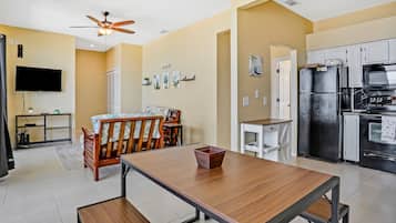 A modern kitchen with a built-in oven, microwave, and refrigerator. There is a dining area with a wooden table and chairs.
