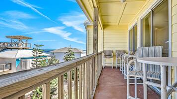 A balcony with a wooden railing, white chairs, and a table.