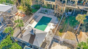 An aerial view of a residential area with a swimming pool, multiple balconies, and a fenced yard.
