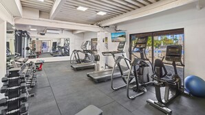 Een fitnessruimte met loopbanden, crosstrainers en gewichten.