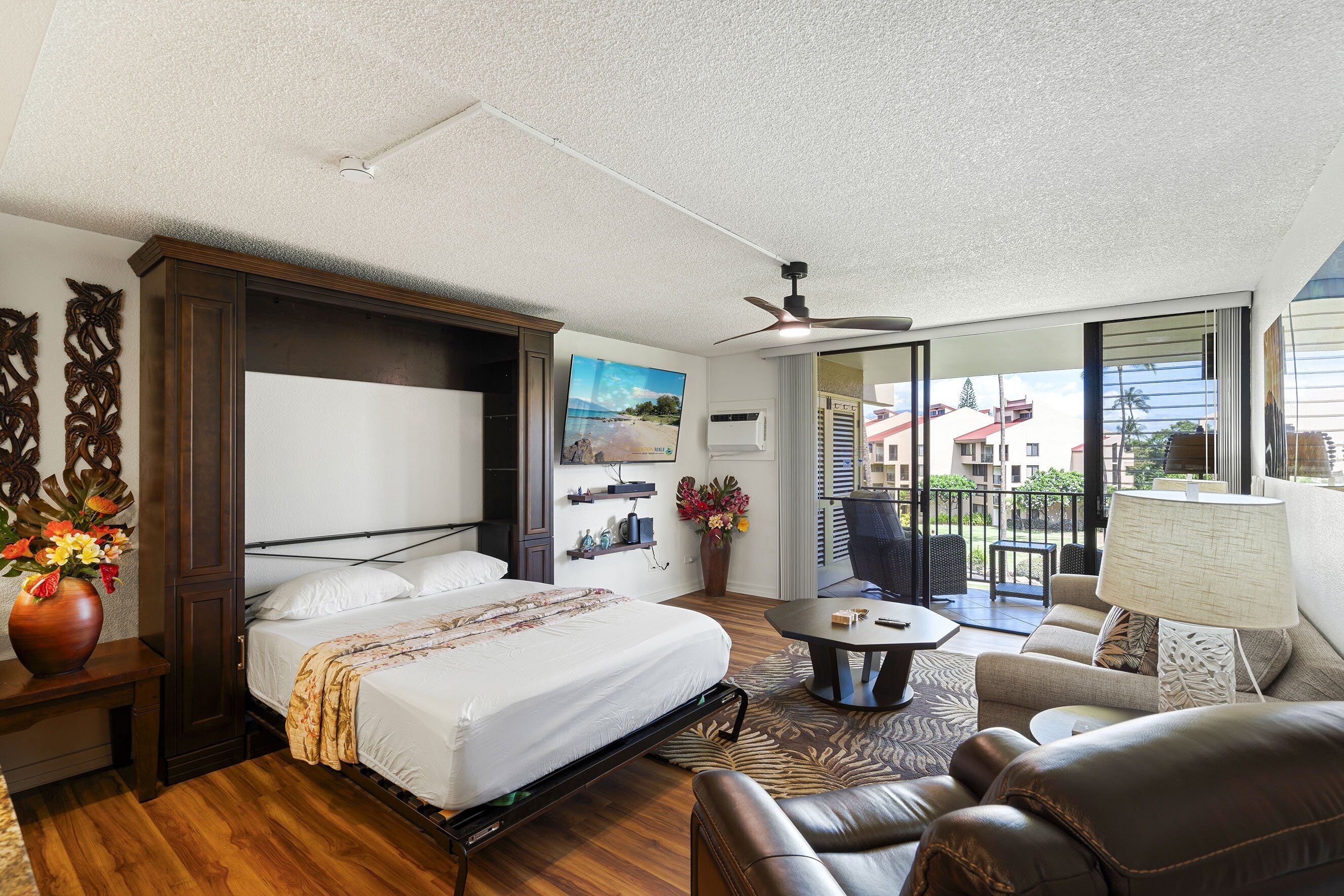 A hotel room with a bed, a sofa, a coffee table, a lamp, and a view of the outside.