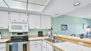 A modern kitchen with white cabinets, a stainless steel stove, and a built-in microwave. - Ormondy A6 - Ocean Shores Getaway (Ormond Beach)