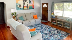 A living room with a sofa, patterned rug, wooden side table, and artwork on the wall. - River Cottage (Edgewater)