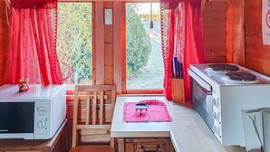 A compact kitchen with a microwave, stove, and a small table with a mat.