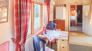 A compact kitchen with a table and chairs, a refrigerator, and a window with curtains.