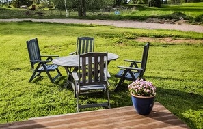 An outdoor dining area with a wooden table and chairs, surrounded by well-maintained grass and a pathway in the background. - 2 bedroom stunning home in Sandhem (Sandhem)