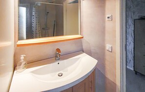 A bathroom with a white sink, a mirror, and a shower visible in the background. - 2 bedroom stunning home in Sandhem (Sandhem)