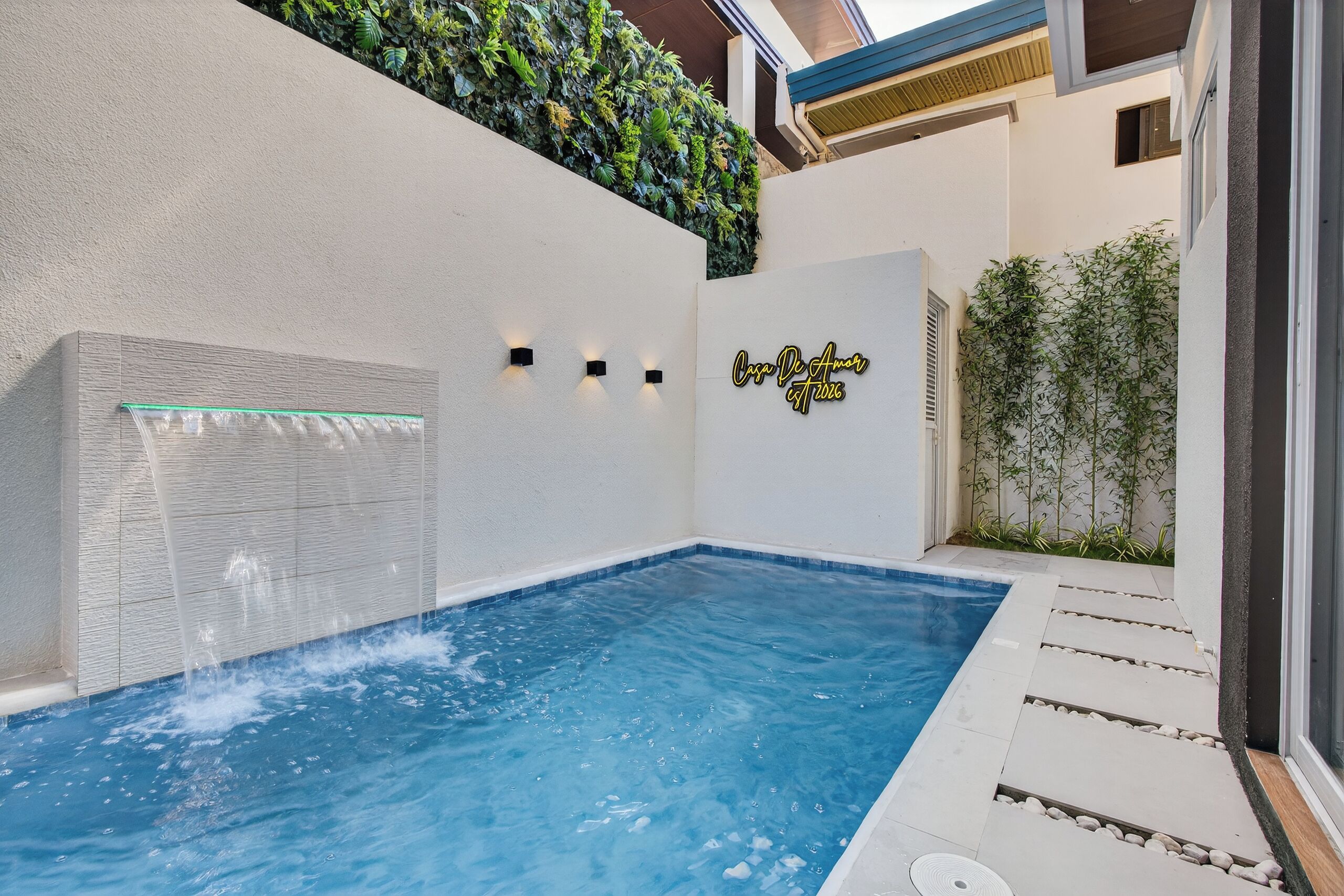 A swimming pool with a glass panel and a wall-mounted light fixture.