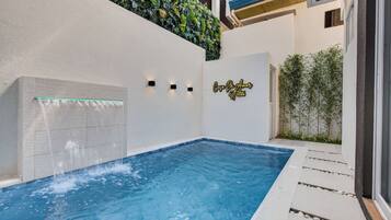 A swimming pool with a glass panel and a wall-mounted light fixture.