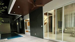 A modern outdoor space with a swimming pool, a covered patio, and a glass door leading to an interior area. - Luxury Villa with Private Pool for Gathering near Davao Airport (Davao)