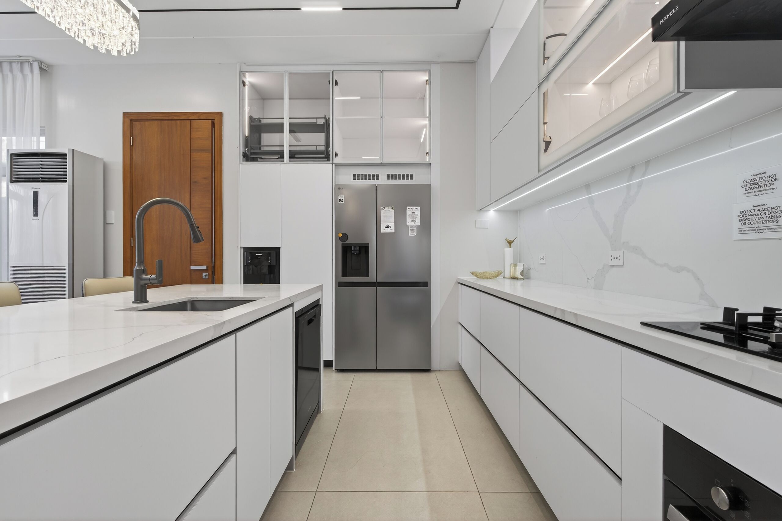 A modern kitchen with white cabinetry, a stainless steel refrigerator, and a built-in dishwasher.