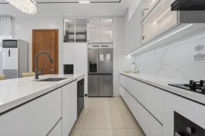 A modern kitchen with white cabinetry, a stainless steel refrigerator, and a built-in dishwasher.