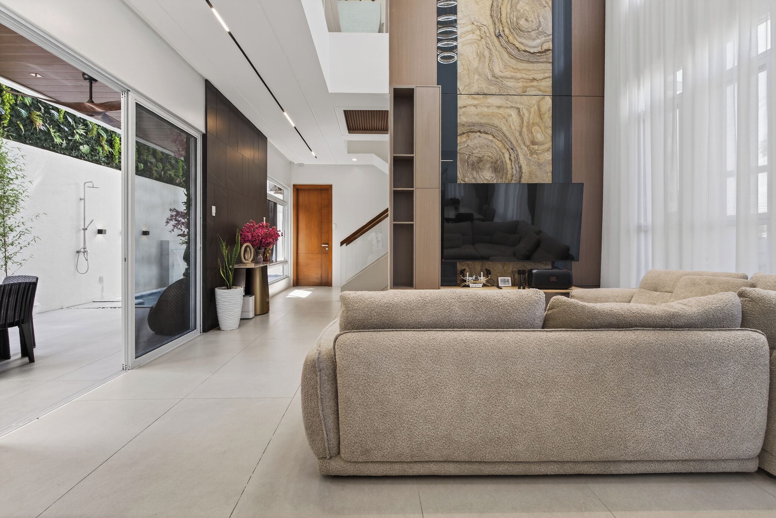 A modern interior with a large, plush sofa, a glass shower enclosure, and a vertical wood panel accent.