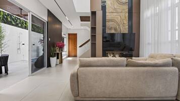 A modern interior with a large, plush sofa, a glass shower enclosure, and a vertical wood panel accent.