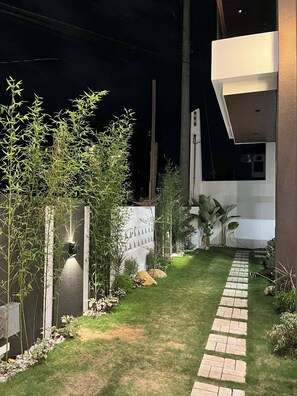 A well-maintained garden with a paved pathway leading to a modern building.