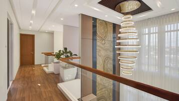 A modern interior with a wooden floor, a glass railing, and a decorative light fixture.