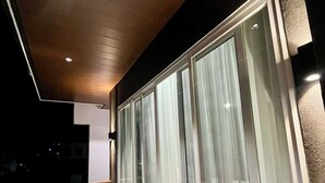 A modern balcony with glass doors and a wooden ceiling. - Luxury Villa with Private Pool for Gathering near Davao Airport (Davao)