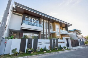 A modern two-story house with a balcony, a garage, and a well-maintained garden.