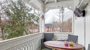 Een overdekt terras met een ronde tafel en stoelen, een vogelkooi en een lantaarn.
