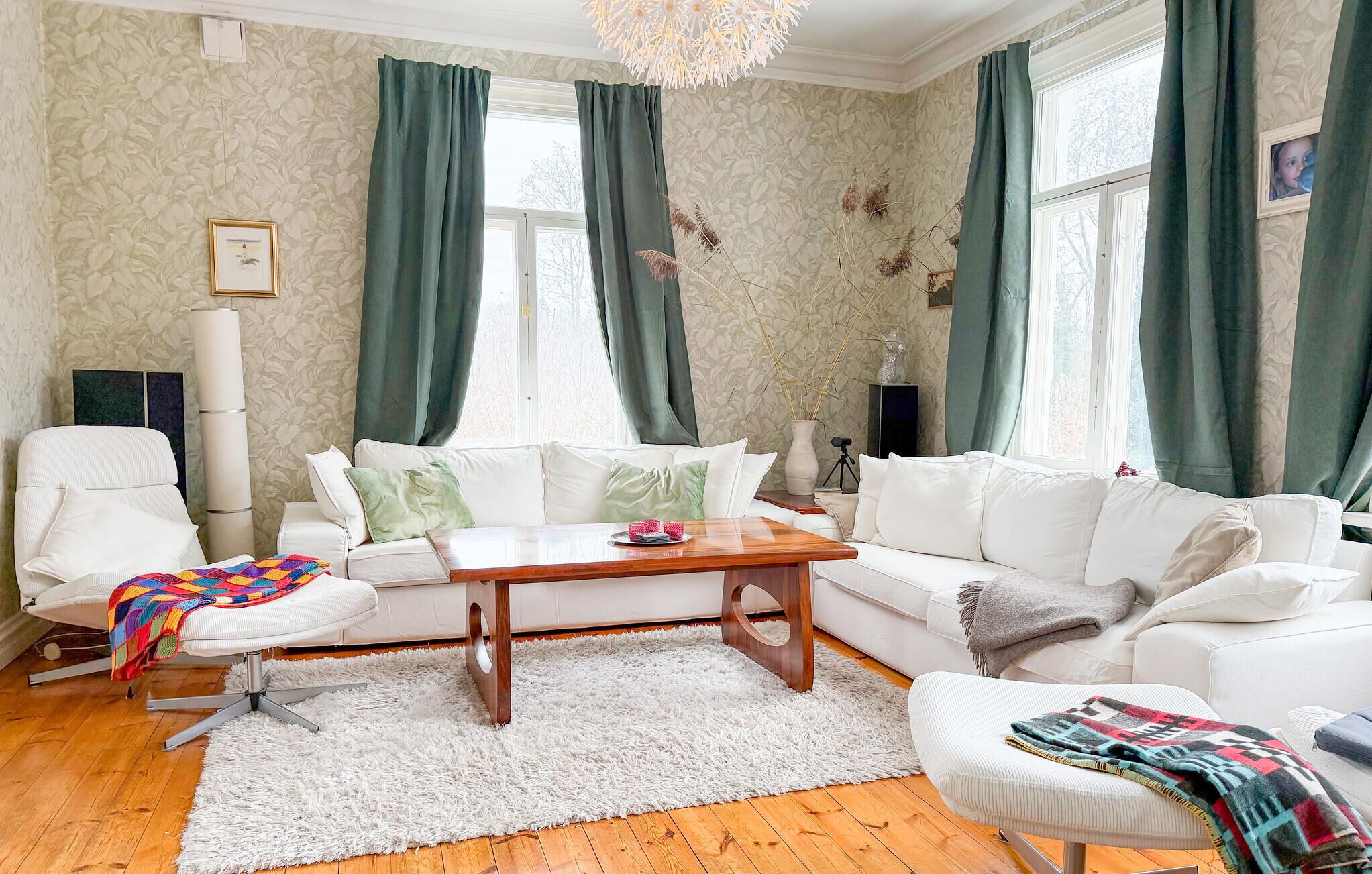 A living room with a white sofa set, a wooden coffee table, and a fluffy white rug.