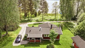 Ein Haus mit Ziegeldach, ein geparktes Auto davor und eine Fahnenstange mit einer Flagge.