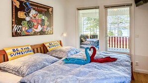 Ein Schlafzimmer mit Bett, Kissen, einem Wandbild und Blick durch eine Tür.