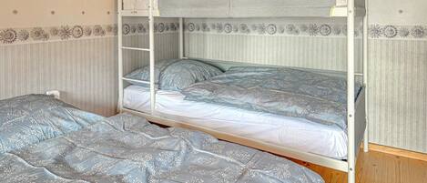 Una cama litera con una escalera, dos camas con ropa de cama de diseño floral y una pared con un dibujo de sol.