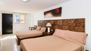 Una habitación de hotel con dos camas, un cabecero de madera, una mesita de noche con lámpara y un cuadro en la pared.