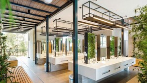 A modern bathroom with multiple sinks, wooden benches, and plants. - Holiday home with terrace (Tar/Poreč)