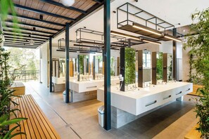 A modern bathroom with multiple sinks, wooden benches, and plants. - Holiday home with terrace (Tar/Poreč)
