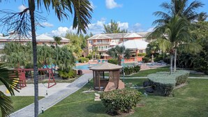 A well-maintained outdoor area with a swimming pool, palm trees, and a gazebo. - Bahamas resort with 2 bedrooms, 2 bathrooms, full kitchen, living room, beach (Freeport)