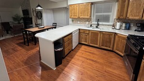 A modern kitchen with wooden cabinets, a central island, and a dining area with chairs and a table. - Serene 3-bedroom townhome in welcoming Evanston perfect for relaxing. (Evanston)