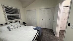 A bedroom with a bed, a window with blinds, a small table with a plant, and a closet with two doors. - Serene 3-bedroom townhome in welcoming Evanston perfect for relaxing. (Evanston)