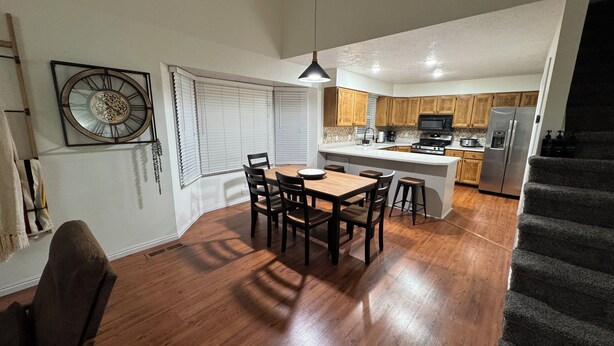 A modern kitchen with wooden cabinets, a central island, and a dining area with a table and chairs. - Serene 3-bedroom townhome in welcoming Evanston perfect for relaxing. (Evanston)