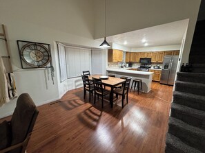 Une cuisine moderne avec des meubles en bois, un îlot central et un coin repas comprenant une table et des chaises.