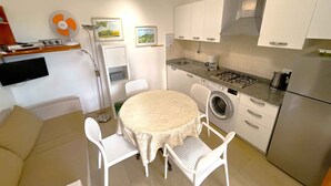 Une cuisine compacte comprenant une table ronde, des chaises, un lave-linge et un réfrigérateur.