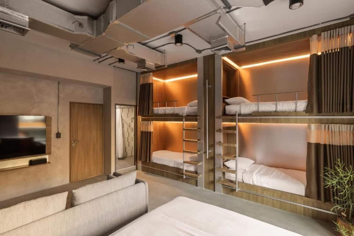 Een moderne hotelkamer met stapelbedden, een bank, een televisie en een garderobe.