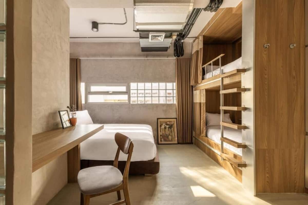 Een kleine slaapkamer met een bed, bureau en ingebouwde houten opbergruimte.