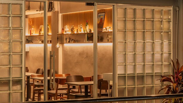 Ein Blick ins Restaurantinnere, mit Bar, Sitzgelegenheiten und einer Zierpflanze.