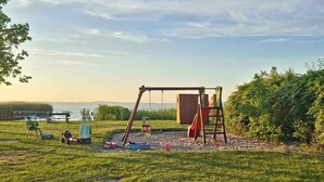 A playground with swings and slides, a picnic table, and a view of the water. - Holiday home near the water with air conditioning and Wi-Fi (Zamárdi)