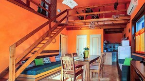 A multi-level room with a wooden staircase, a dining area with a table and chairs, and a kitchen area with a refrigerator and microwave. - Holiday home near the water with air conditioning and Wi-Fi (Zamárdi)