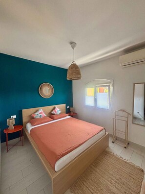 A bedroom with a bed, a hanging light, a mirror, a window, and a small table. - Holiday home with air conditioning and garden (Isola di Albarella)