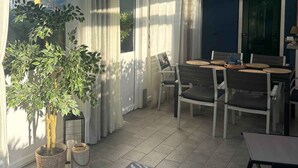 Een terras buiten met een tafel, stoelen, een plafondventilator en uitzicht op de lucht.