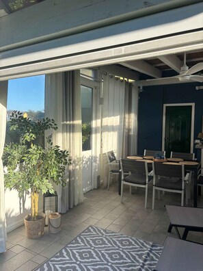 An outdoor patio with a table and chairs, a ceiling fan, and a view of the sky. - Holiday home with air conditioning and garden (Isola di Albarella)