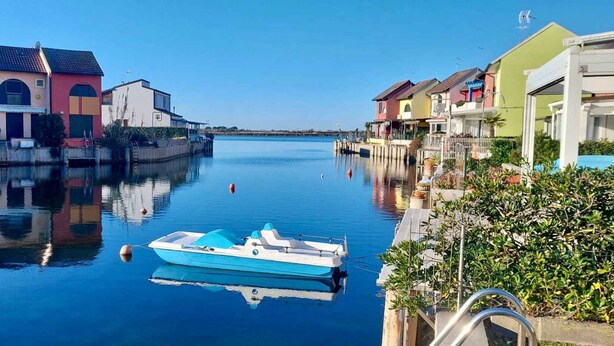 Een rustig water met een aangemeerd schip, omringd door kleurrijke gebouwen.