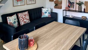 Een moderne woonkamer met een trap, een eettafel en een bank met decoratieve kussens.