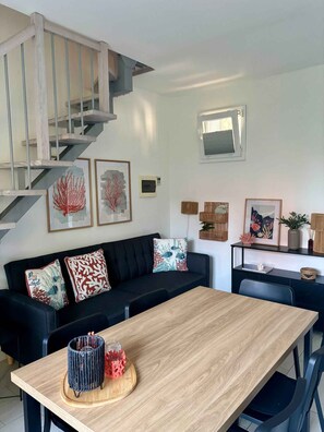 A modern living room with a staircase, a dining table, and a sofa with decorative pillows. - Holiday home with air conditioning and garden (Isola di Albarella)
