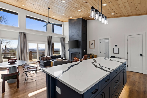A modern kitchen with a large island, wooden ceiling, and large windows. - Private Luxe Cabin: Views+EV Charger+Hot Tub+Fire Pit+Bowling+Kids Play Area (Mineral Bluff)